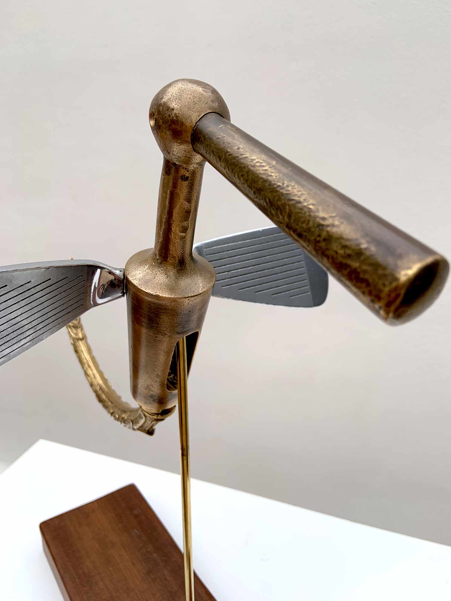 Sculptural bird made from golf club heads mounted on a wooden base – detail