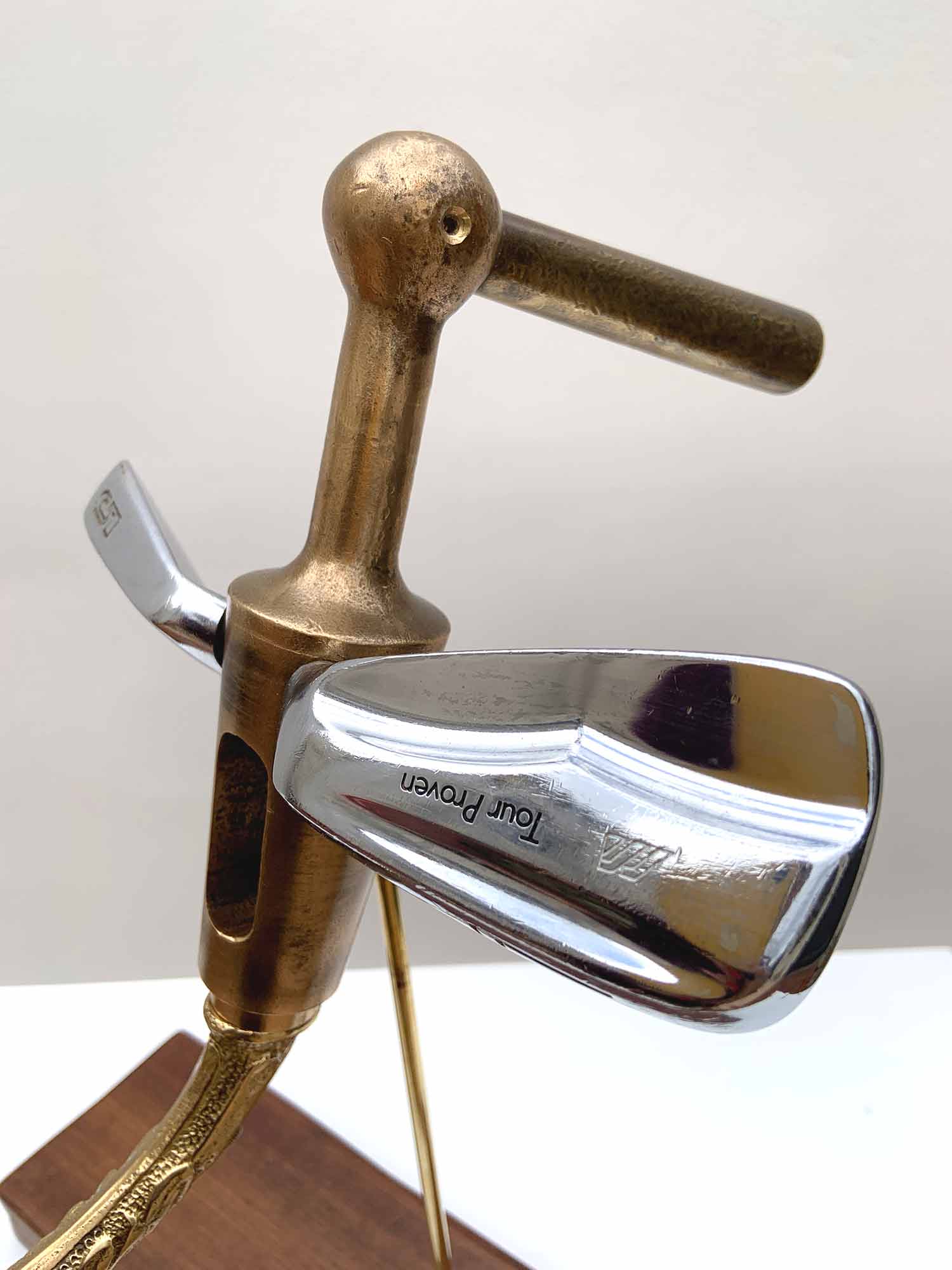 Sculptural bird made from golf club heads mounted on a wooden base – detail