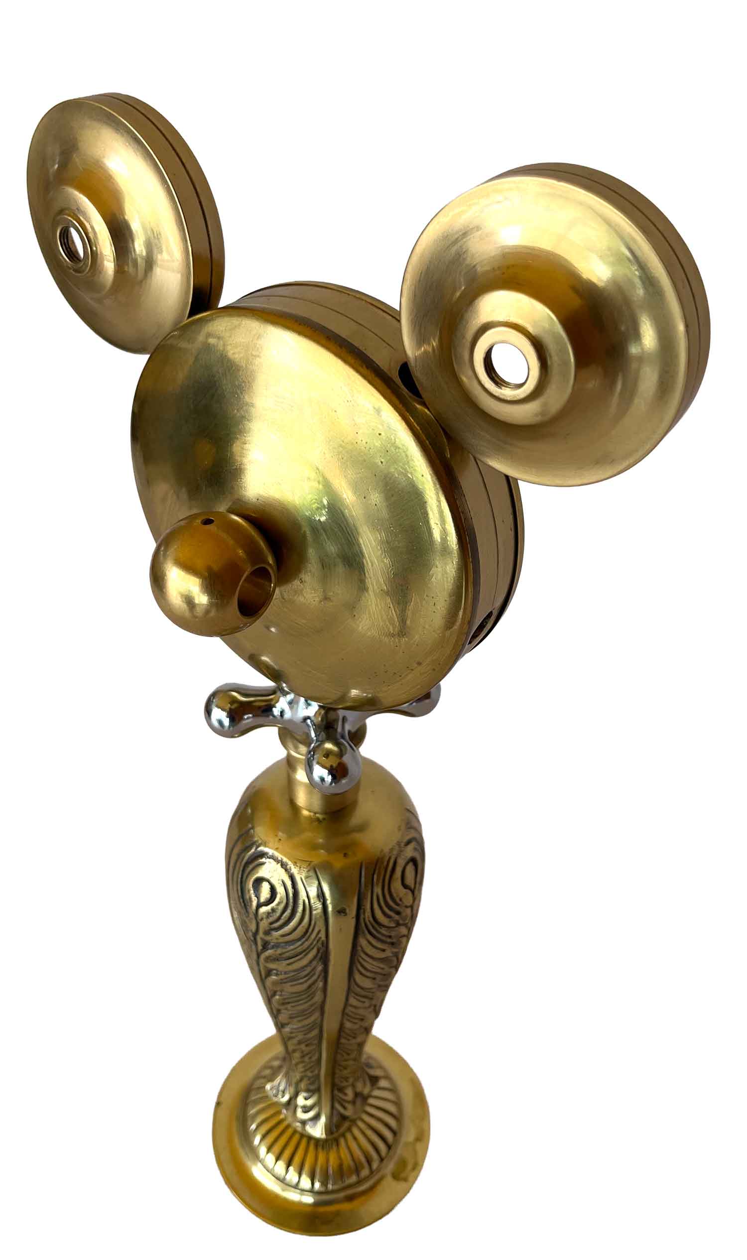 Una escultura dorada con el cuerpo y las piernas decorados con motivos ornamentados, y una pieza con forma de maneta que hace las veces de collar.
