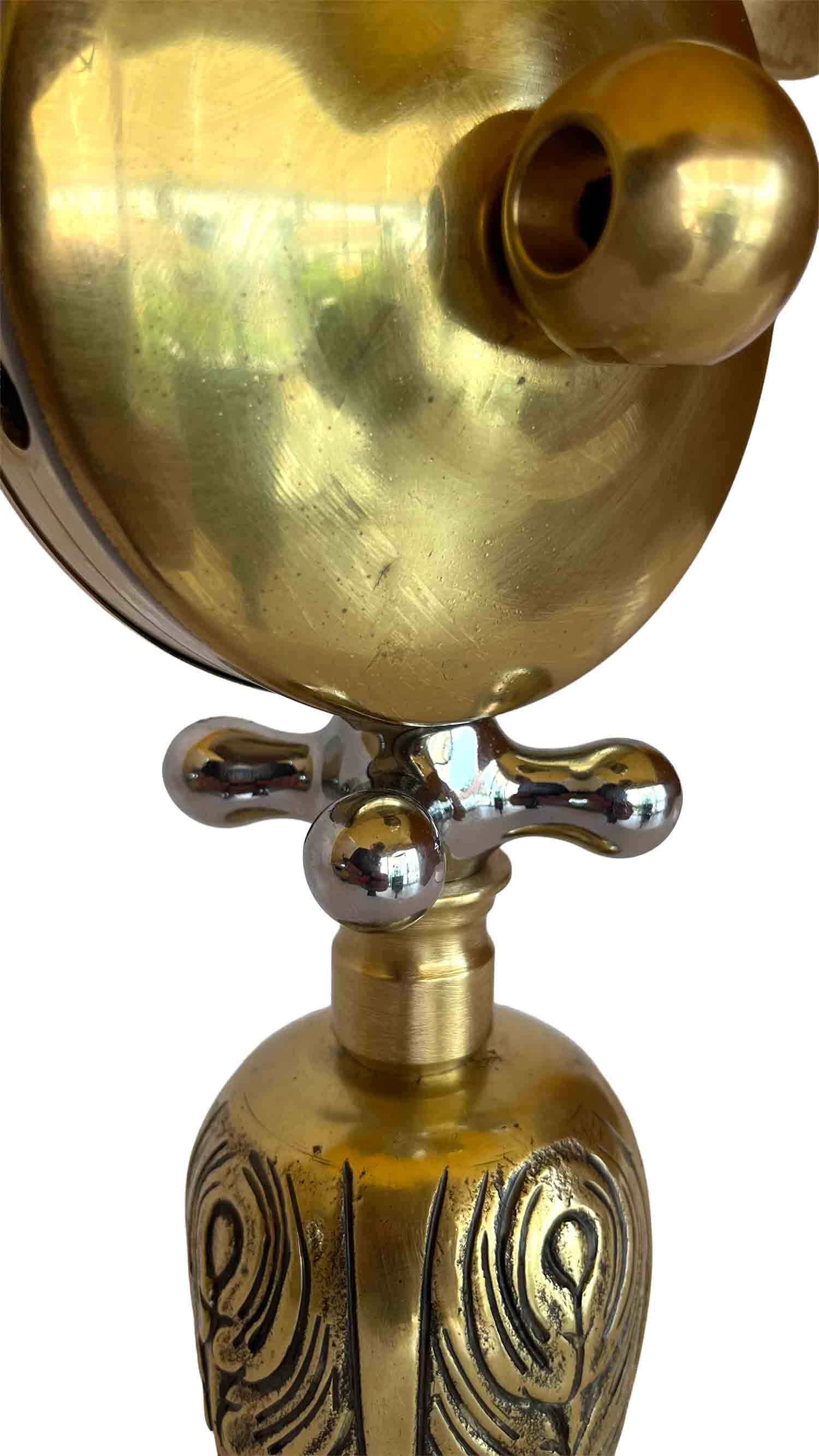 Una escultura dorada con el cuerpo y las piernas decorados con motivos ornamentados, y una pieza con forma de maneta que hace las veces de collar.