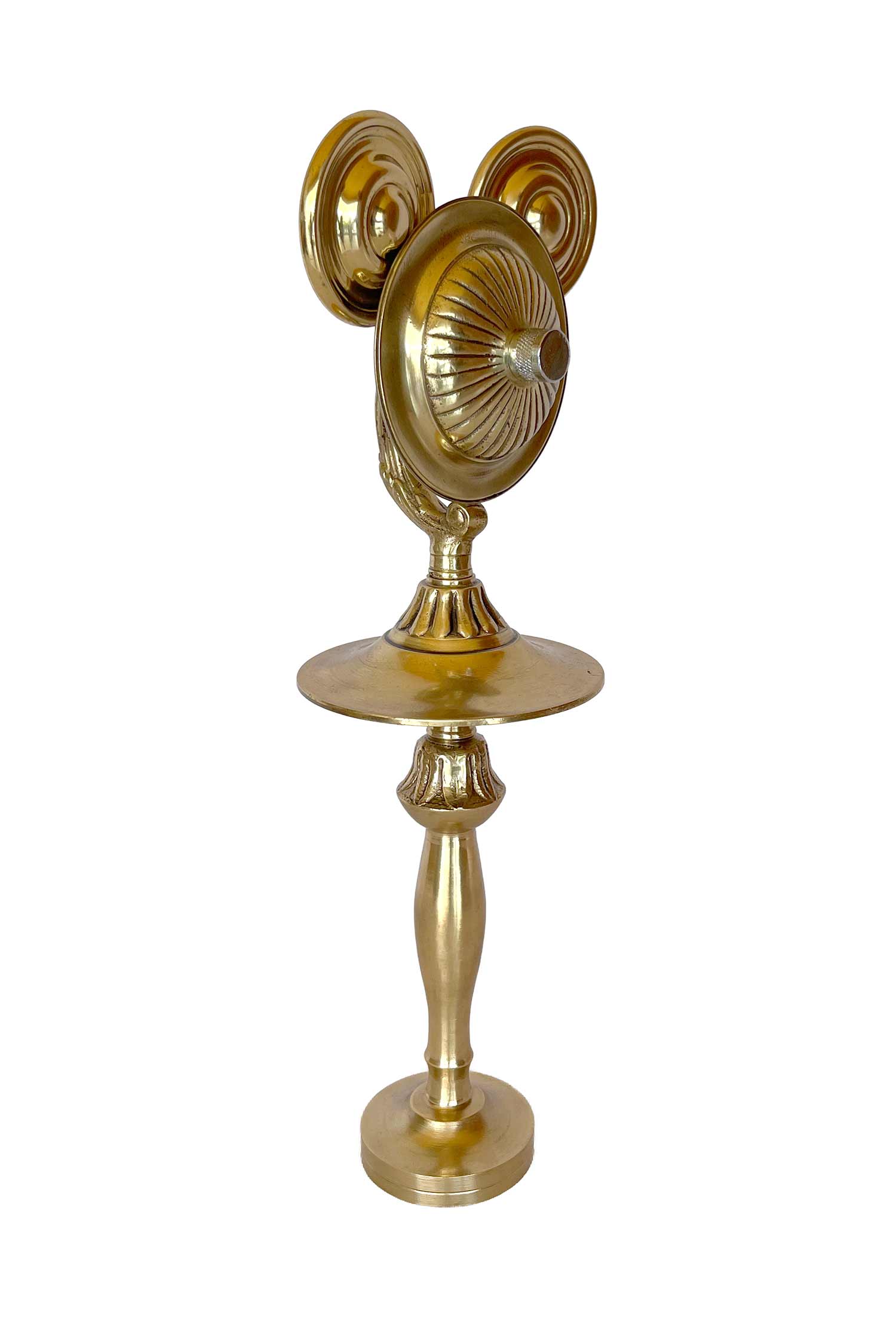 Una escultura dorada con el rostro marcado por rayas que parecen rayos de sol, que lleva una barba postiza y cuyas piernas surgen de un candelabro.