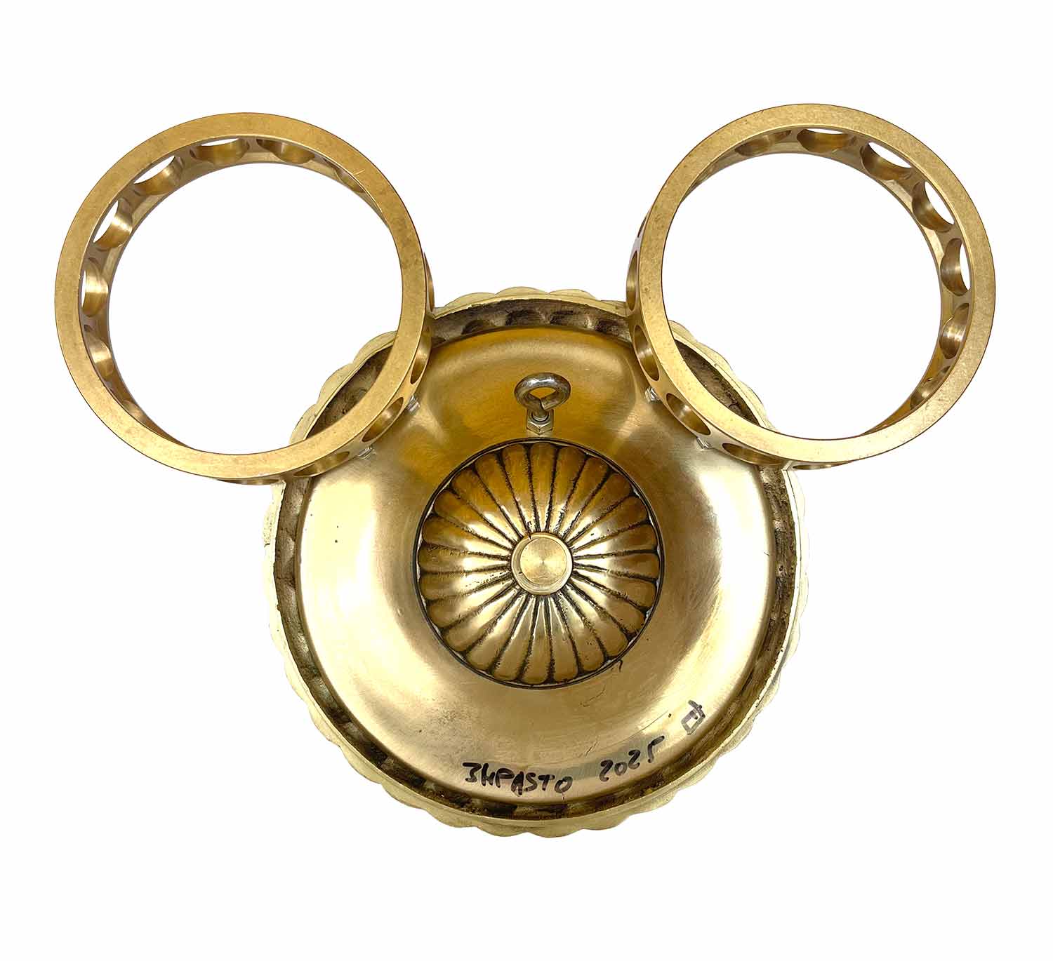 Una escultura con la cara de Mickey para colgar en la pared, hecha con una pantalla de lámpara con rayas radiales como las del sol y dos círculos industriales a modo de orejas: la parte trasera y la firma.