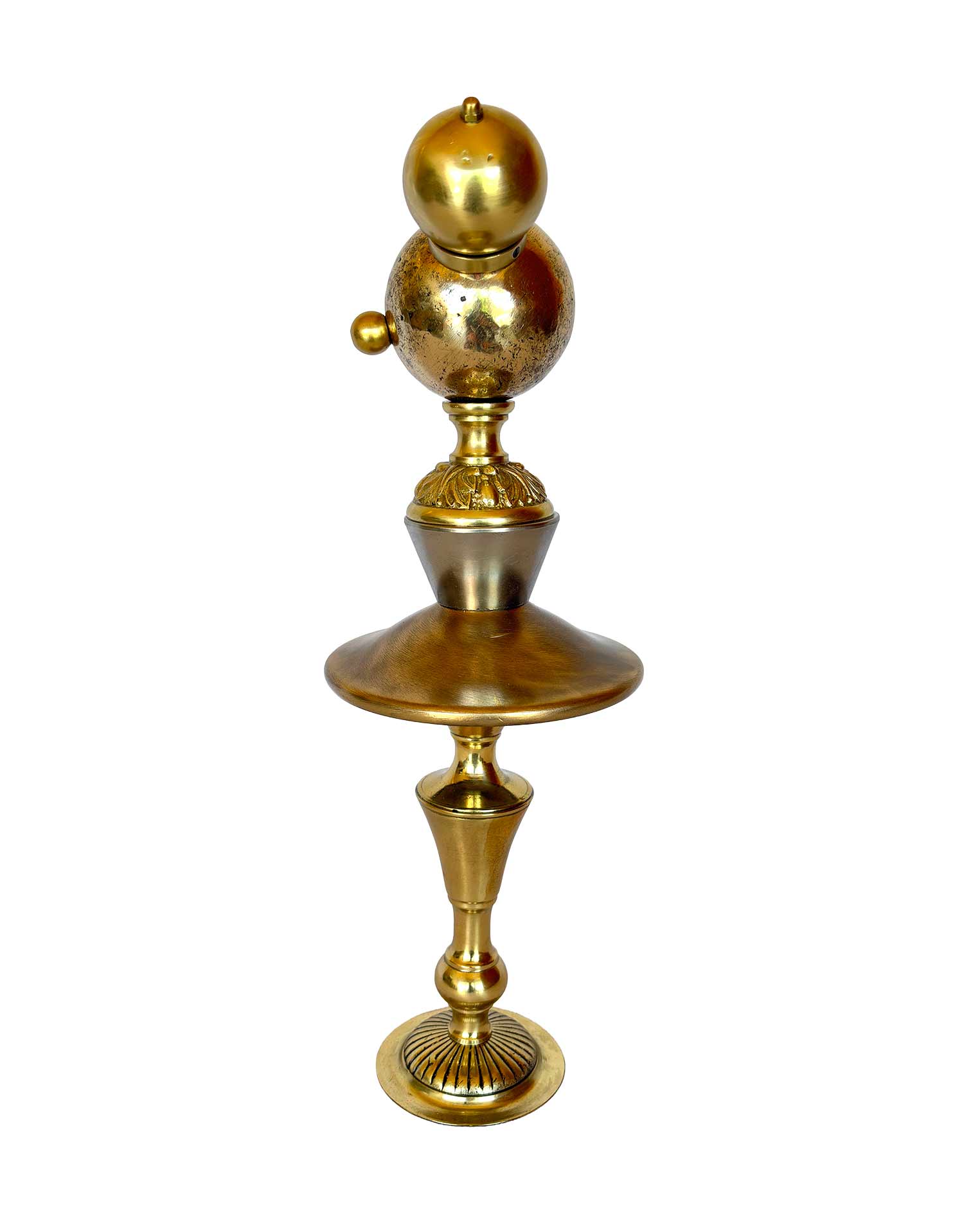 Una escultura dorada con una bola de petanca en cada cara y dos pomos a modo de orejas; el cuerpo y las piernas también están dorados y están hechos con piezas de pantallas de lámpara.